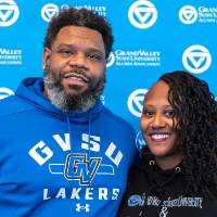 Two event attendees posing for photo in front of Grand Valley backdrop